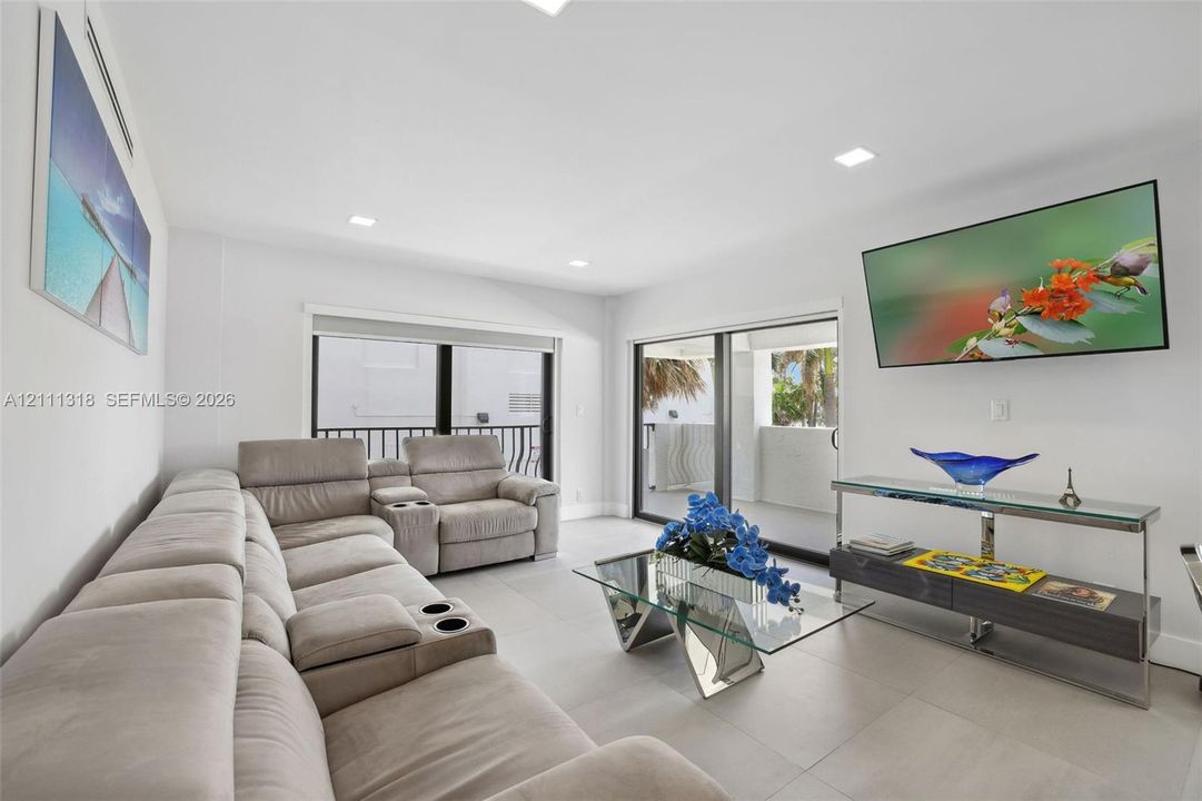 Large-format tile flooring, recessed ceiling lighting, and dual sliding glass doors providing outdoor access