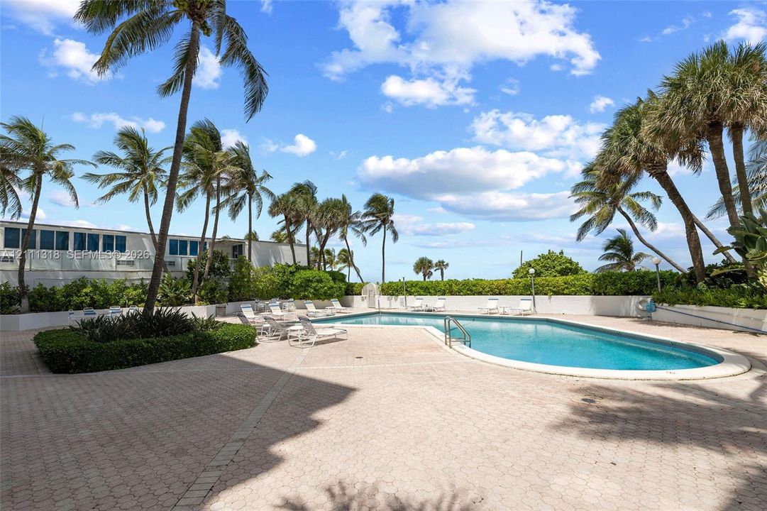 Swimming pool with paved surround, tropical landscaping, and palm trees