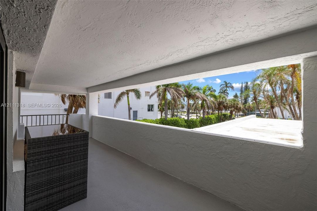 Covered balcony featuring a textured stucco ceiling, solid walls, and an integrated metal railing