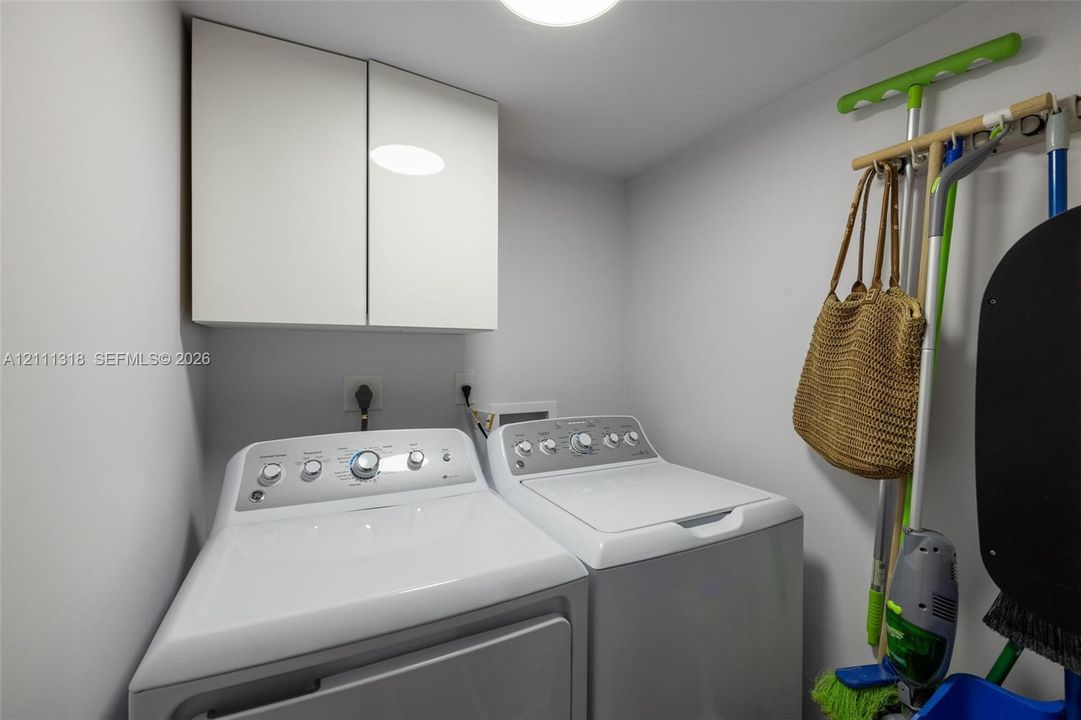 Laundry area featuring white cabinetry and wall-mounted storage hardware