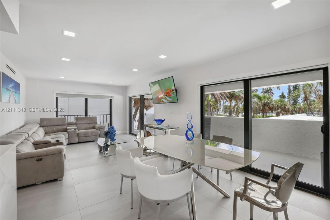 Large-format tile flooring, recessed ceiling lighting, and expansive sliding glass doors providing access to the exterior balcony