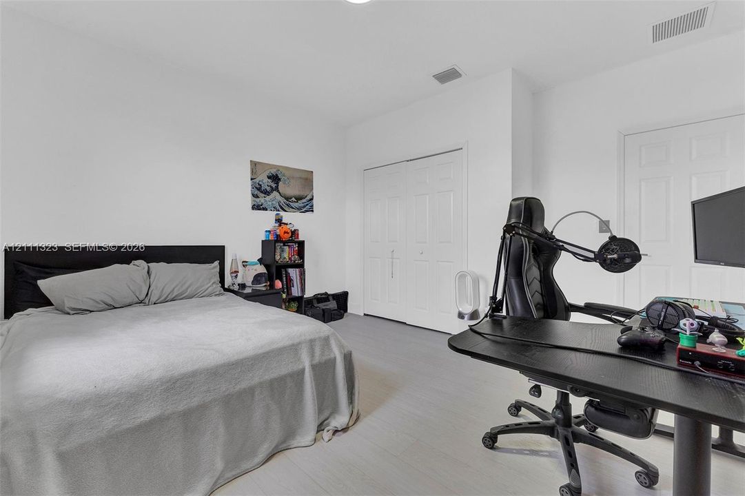 Neutral-toned interior space featuring wood-finish flooring, white walls, and a multi-panel closet with white doors