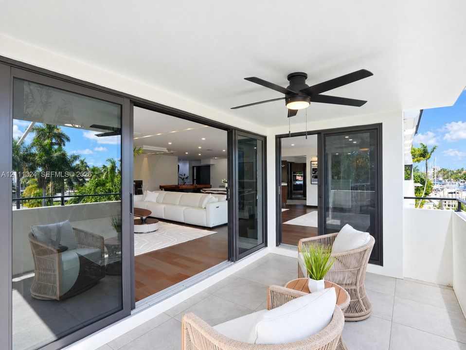 Covered balcony featuring oversized porcelain tile flooring, black-framed sliding glass doors, and an integrated LED ceiling fan