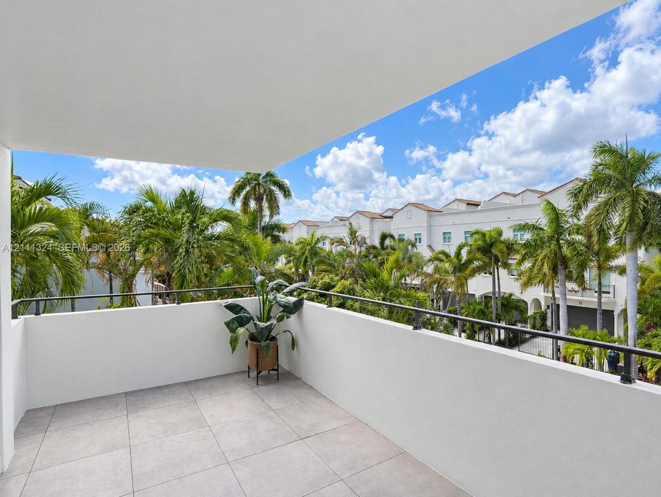 SW-Covered balcony featuring neutral stone-finish tile flooring and a black metal railing