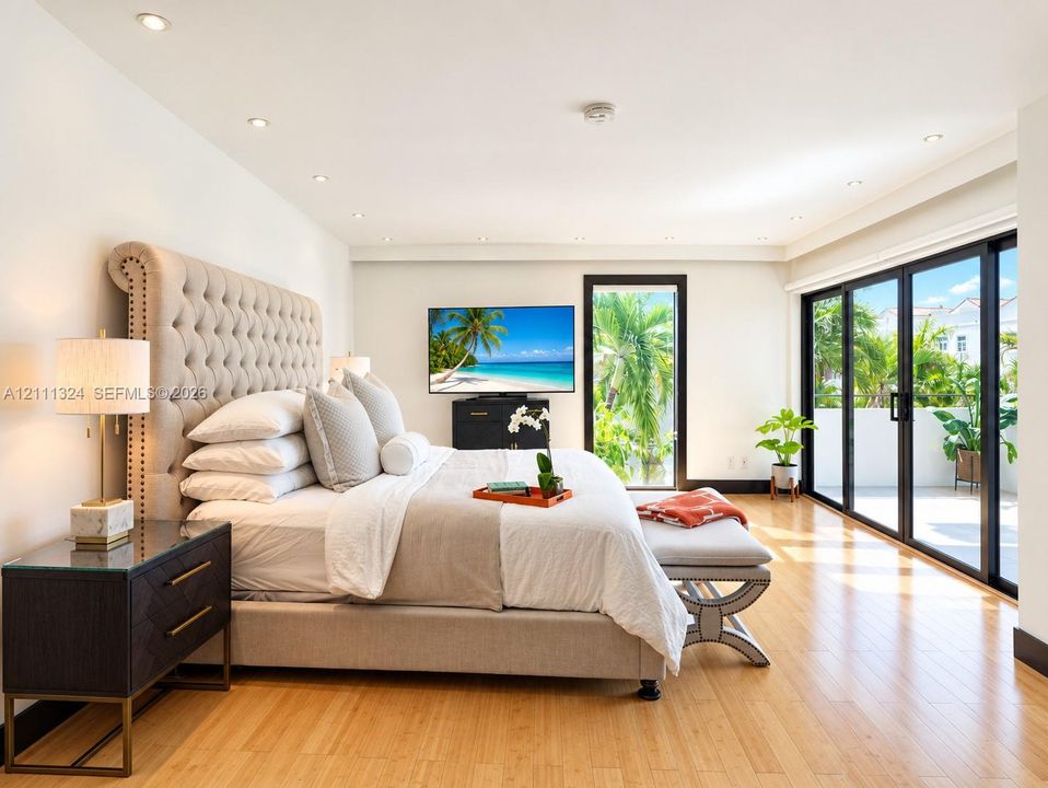 Room featuring wood-finish flooring, recessed lighting, and expansive floor-to-ceiling multi-panel sliding glass doors leading to an exterior balcony