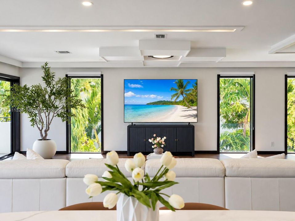 Living area featuring high-contrast black-trimmed windows, recessed ceiling lighting, a custom coffered ceiling detail, and wood-finish flooring