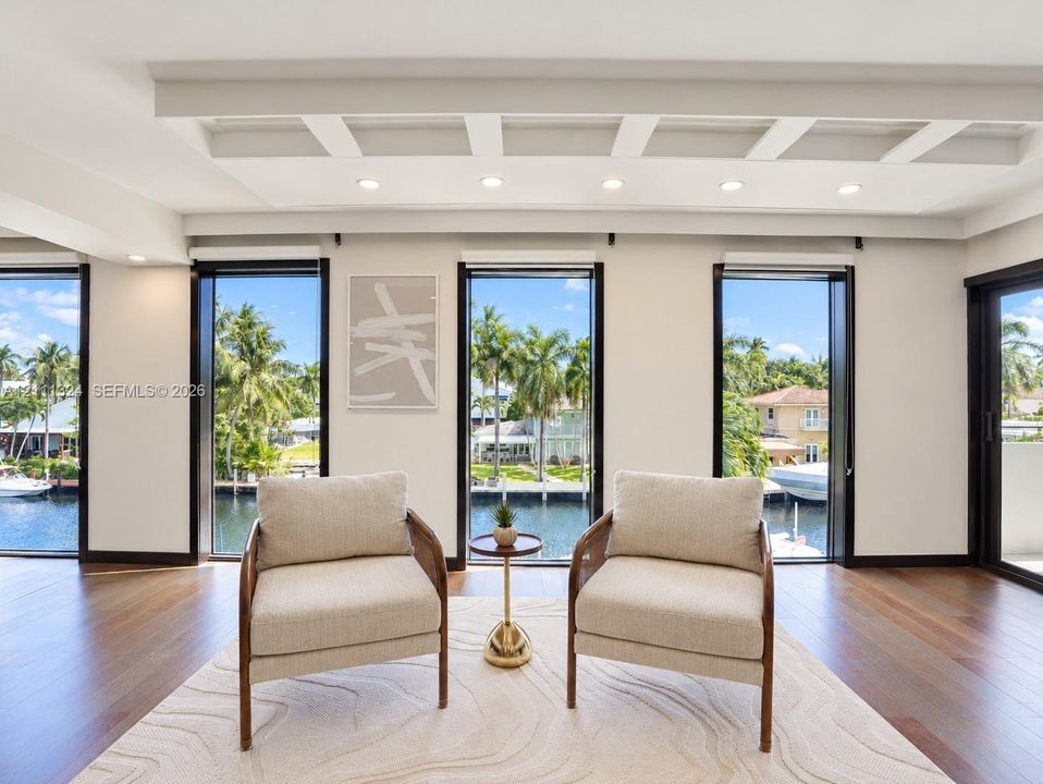 Coffered ceiling with recessed lighting, wood-finish flooring, and floor-to-ceiling windows featuring water frontage
