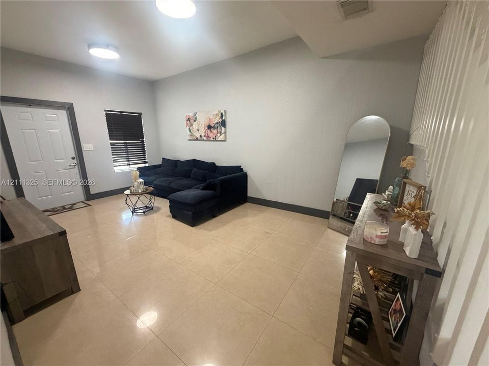 Large-format tile flooring, flush-mount ceiling lighting, and a multi-paneled entry door with dark trim accents