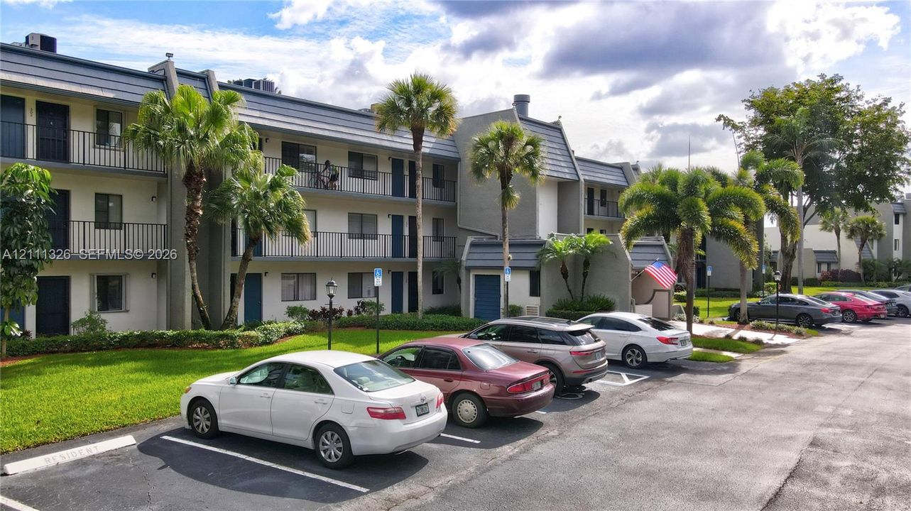 Multi-level exterior featuring a grey facade, tiered balcony railings and plentiful parking spaces.