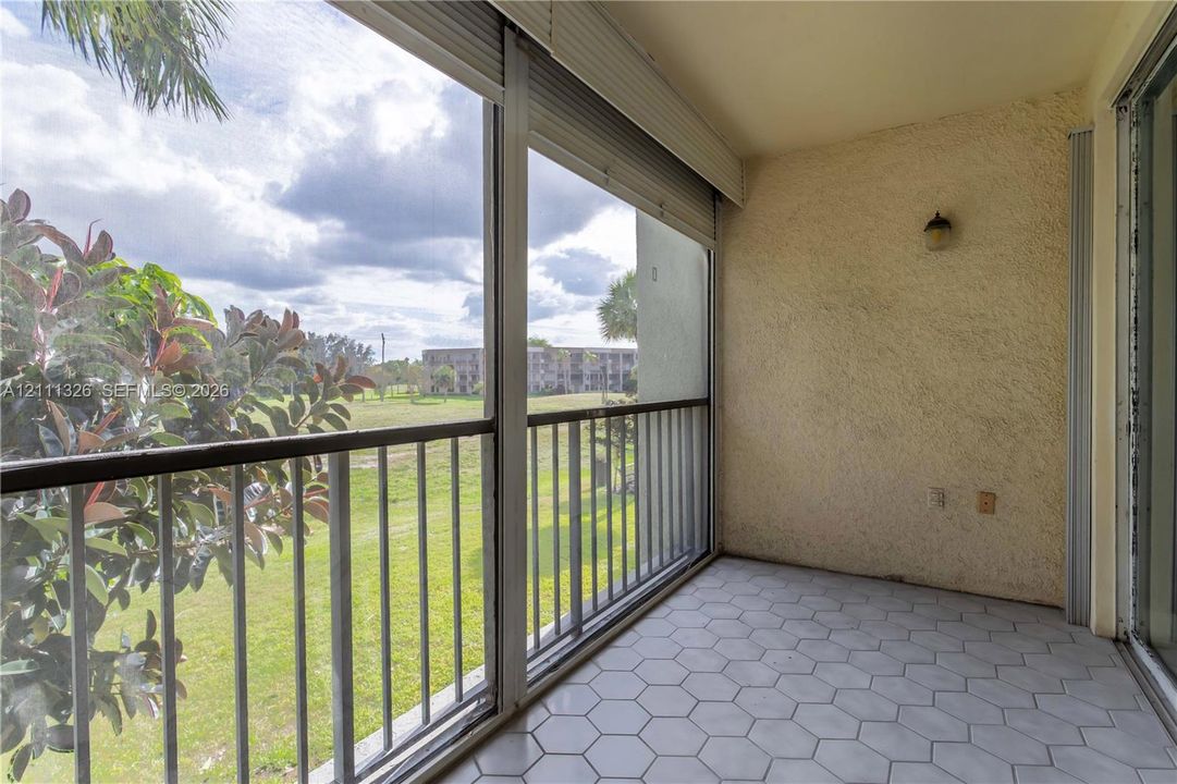 Screened-in balcony featuring hexagonal tile flooring, metal railings, textured wall finish and beautiful view.