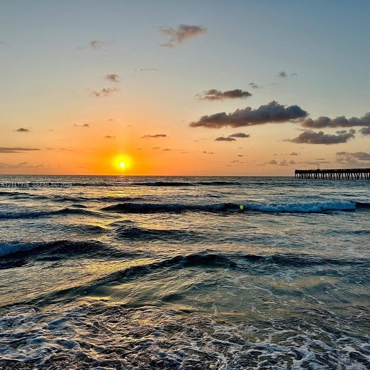 Oceanfront direct expanse of open water, rolling waves, and Lake Worth Beach pier at sunrise.