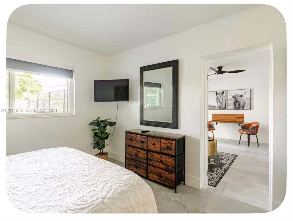 Neutral-toned interior featuring large-format tile flooring, light-filled window, and ceiling-mounted fan fixture