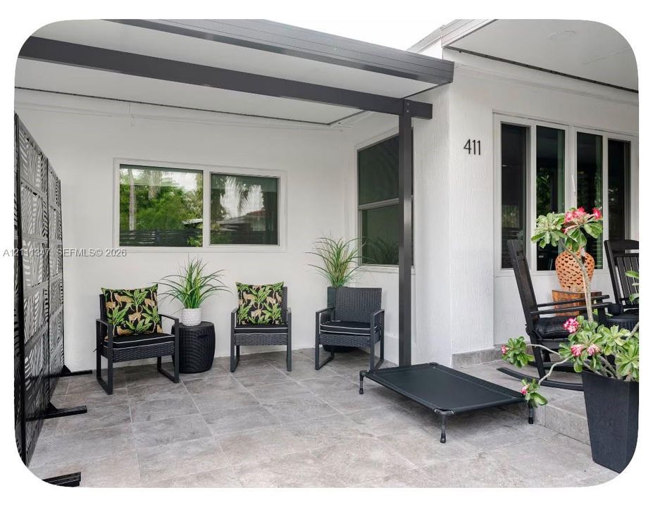 Covered patio featuring large-format stone tile flooring, structural metal support beams, and white exterior wall finish