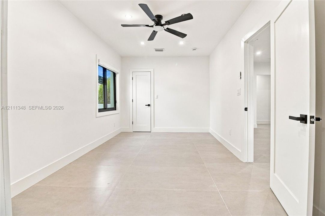 Neutral-toned tile flooring, black matte hardware, recessed lighting, ceiling fan, and solid-core interior doors