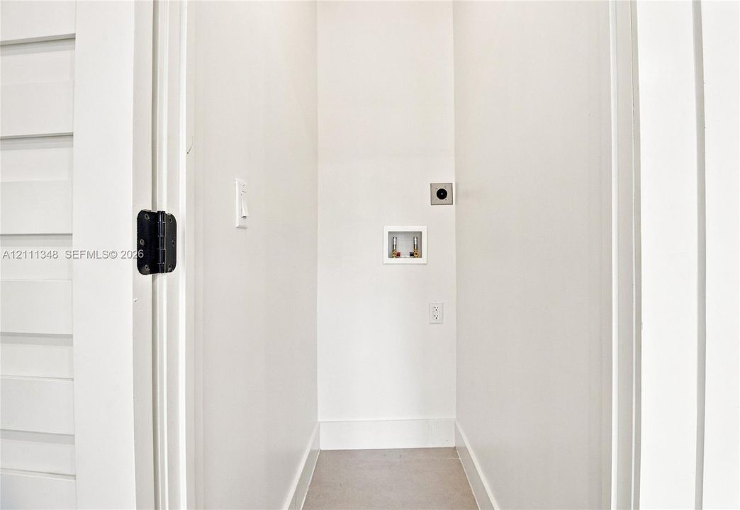Dedicated utility space featuring a recessed water hookup, dedicated electrical outlet, and neutral wall finishes