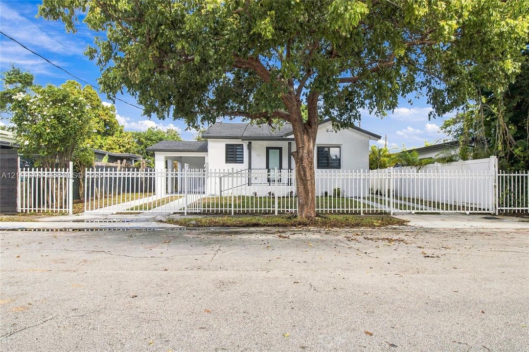 Single-story residence featuring a white exterior, a covered entryway, a gated perimeter, and a paved driveway