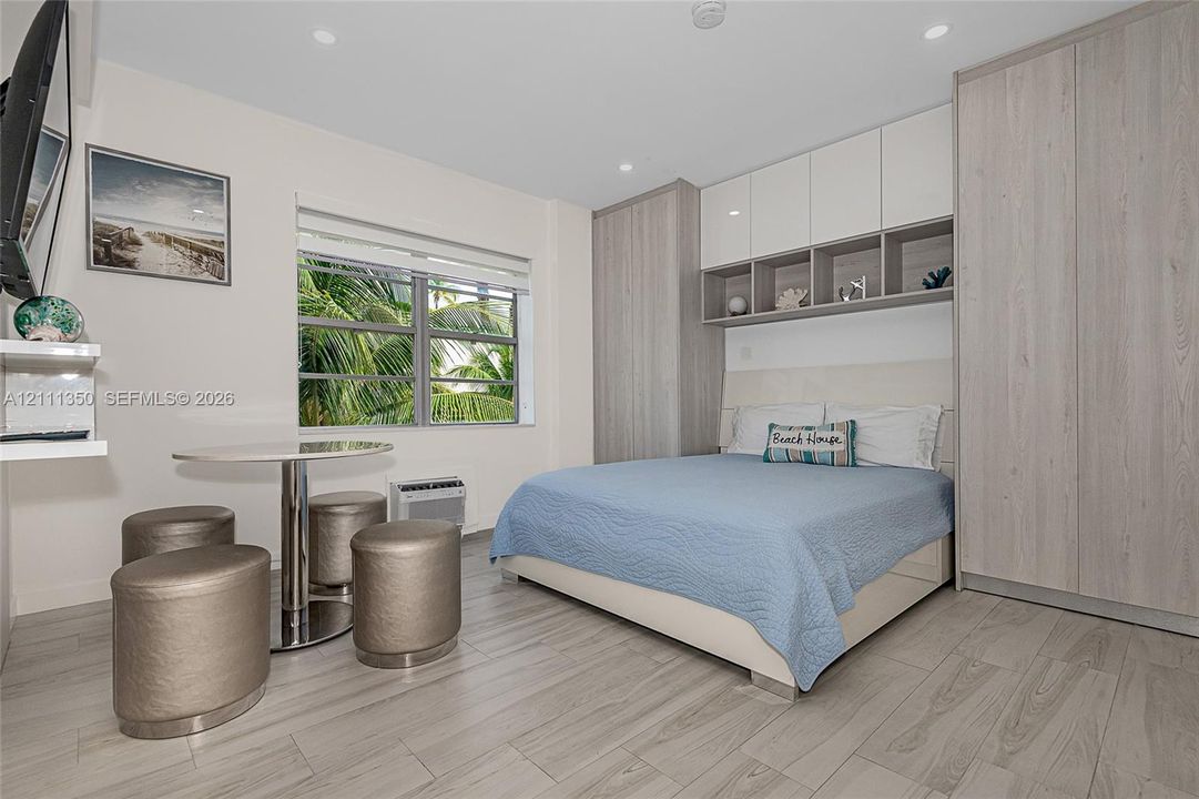 Custom floor-to-ceiling cabinetry with integrated storage, wood-finish flooring, recessed lighting, and dual-pane window
