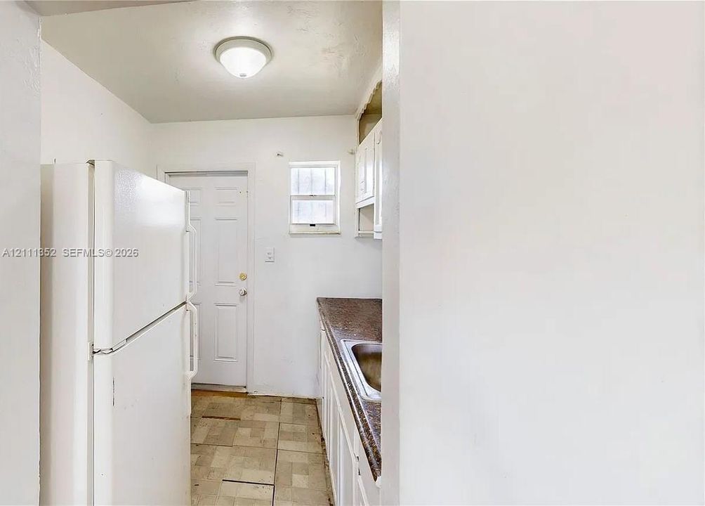 Kitchen featuring solid-surface countertops, integrated sink, white cabinetry, tile flooring, and a flush-mount ceiling light fixture