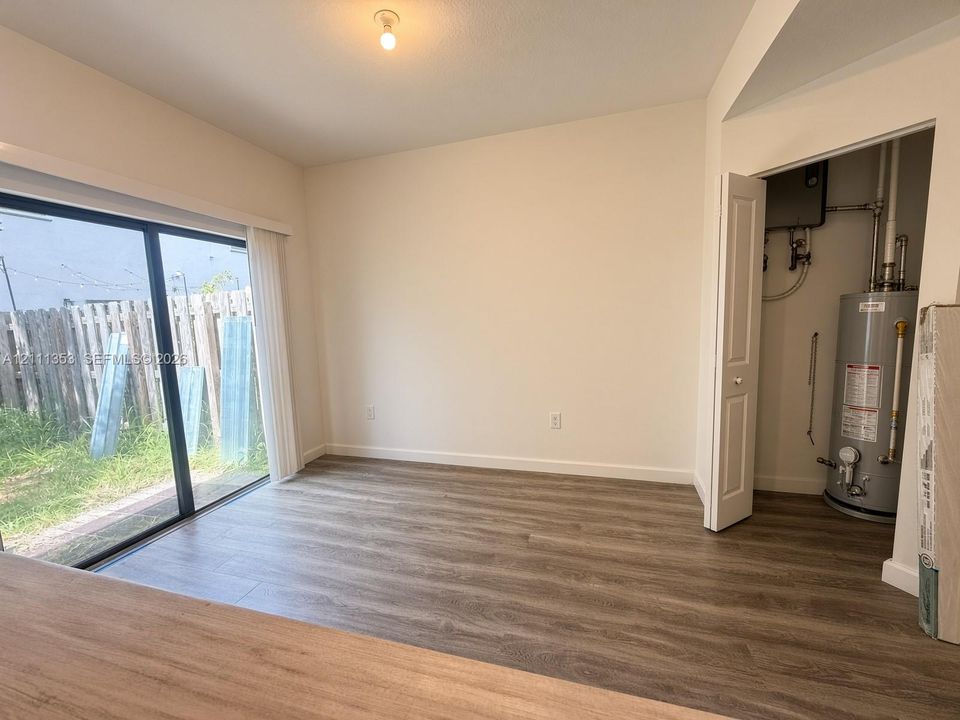 Wood-finish flooring, sliding glass door, and interior utility closet containing a water heater