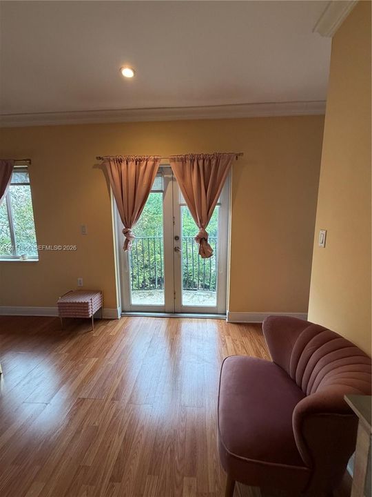 Wood-finish flooring, glass-paneled double doors, and private balcony with iron railing