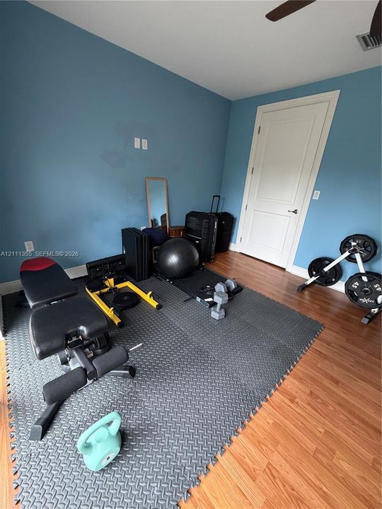 Interior room featuring wood-finish flooring, a solid-core paneled door, and a ceiling fan
