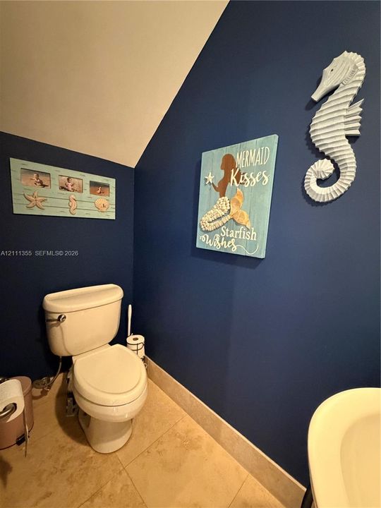 Restroom featuring bold navy blue wall paint and neutral stone-finish floor tiling