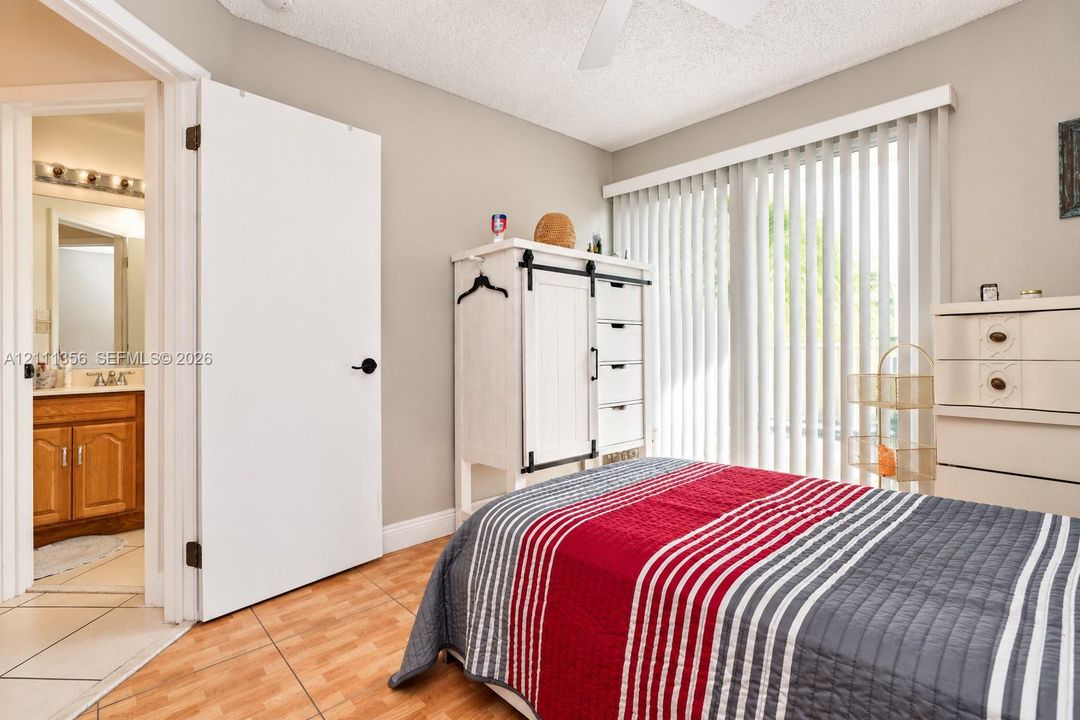 Room featuring ceramic tile flooring, neutral wall paint, vertical window blinds, and a white ceiling fan
