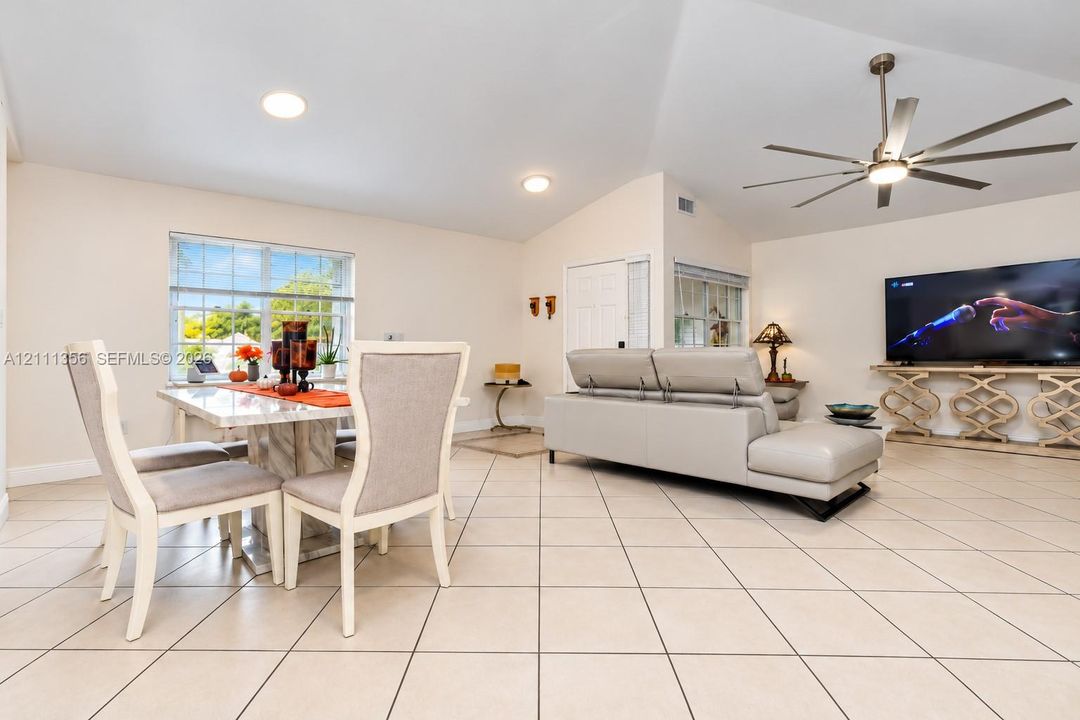 Open-concept interior featuring vaulted ceilings, oversized tile flooring, recessed lighting, and a multi-blade ceiling fan