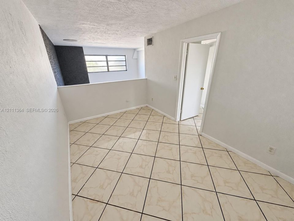Interior space featuring diagonal tile flooring, a charcoal-toned textured brick accent wall, and a multi-pane window