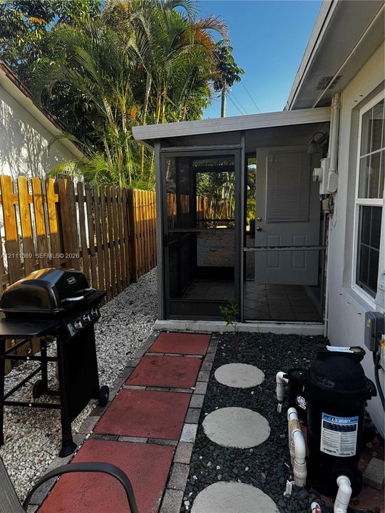 Screened-in porch with tiled flooring, vertical wood-plank perimeter fencing, and concrete paver walkway