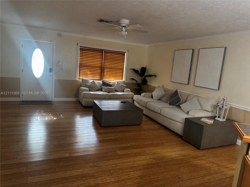 Wood-finish flooring, white exterior door with an oval glass insert, dual-tone wall treatment with chair rail, and a ceiling-mounted fan