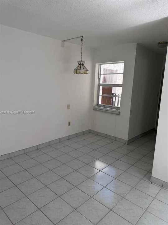 Neutral-toned tile flooring, white wall finish, single-hung window with metal framing, and a decorative hanging pendant light fixture