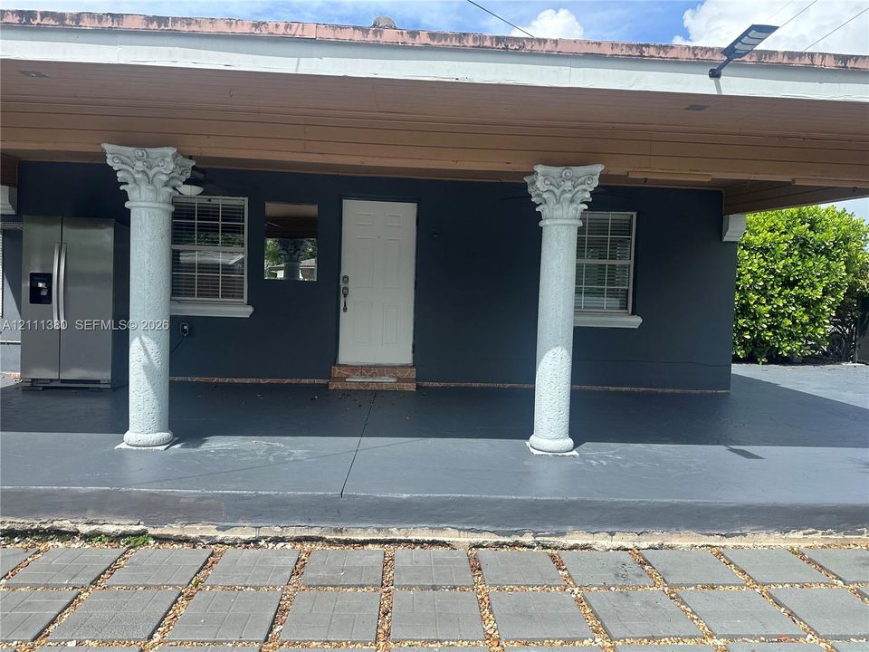 Covered front porch featuring two decorative Corinthian-style columns, recessed ceiling lighting, and multi-pane windows
