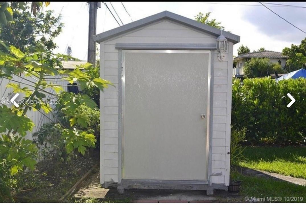 Detached storage structure featuring horizontal siding, a gabled roofline, and an integrated exterior light fixture