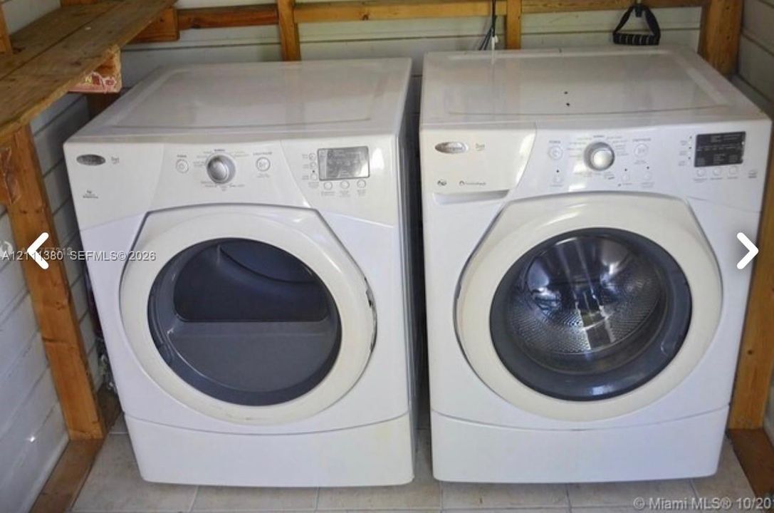 White front-loading washer and dryer set, wood-frame shelving, and tiled flooring
