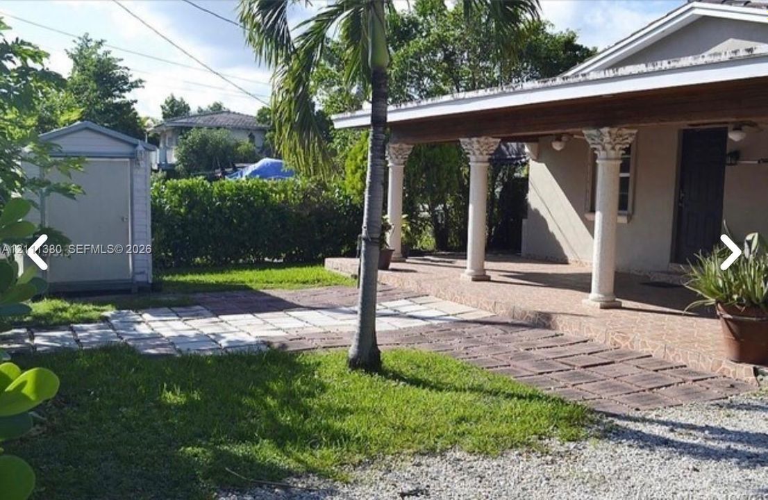 Covered porch with decorative columns, stone-tile flooring, and a stone-paver walkway