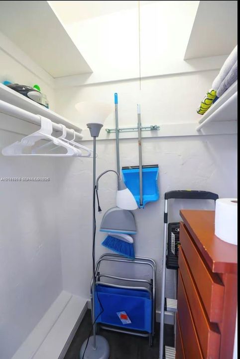 Storage space featuring dual upper shelving and a clothes hanging rod