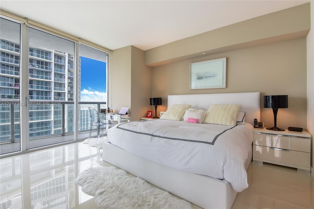 Floor-to-ceiling glass wall, expansive private balcony, and polished stone flooring
