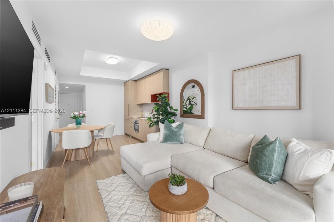Light-toned wood-finish flooring, custom flat-panel light wood cabinetry, recessed tray ceiling lighting, and flush-mount modern overhead lighting