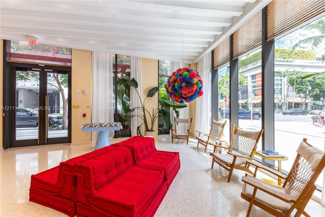 Expansive lobby featuring floor-to-ceiling windows, high exposed-beam ceilings, and terrazzo flooring