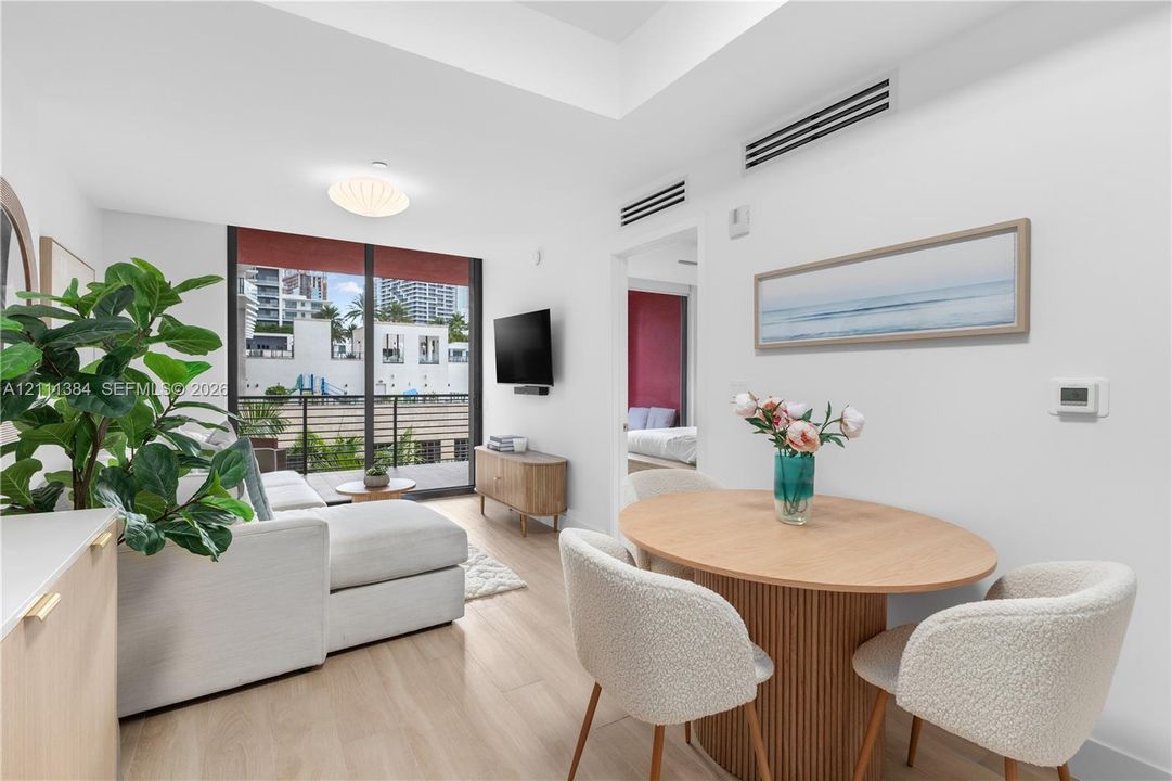 Interior space featuring wood-finish flooring, tray ceiling, floor-to-ceiling glass sliding doors, and private balcony with railing