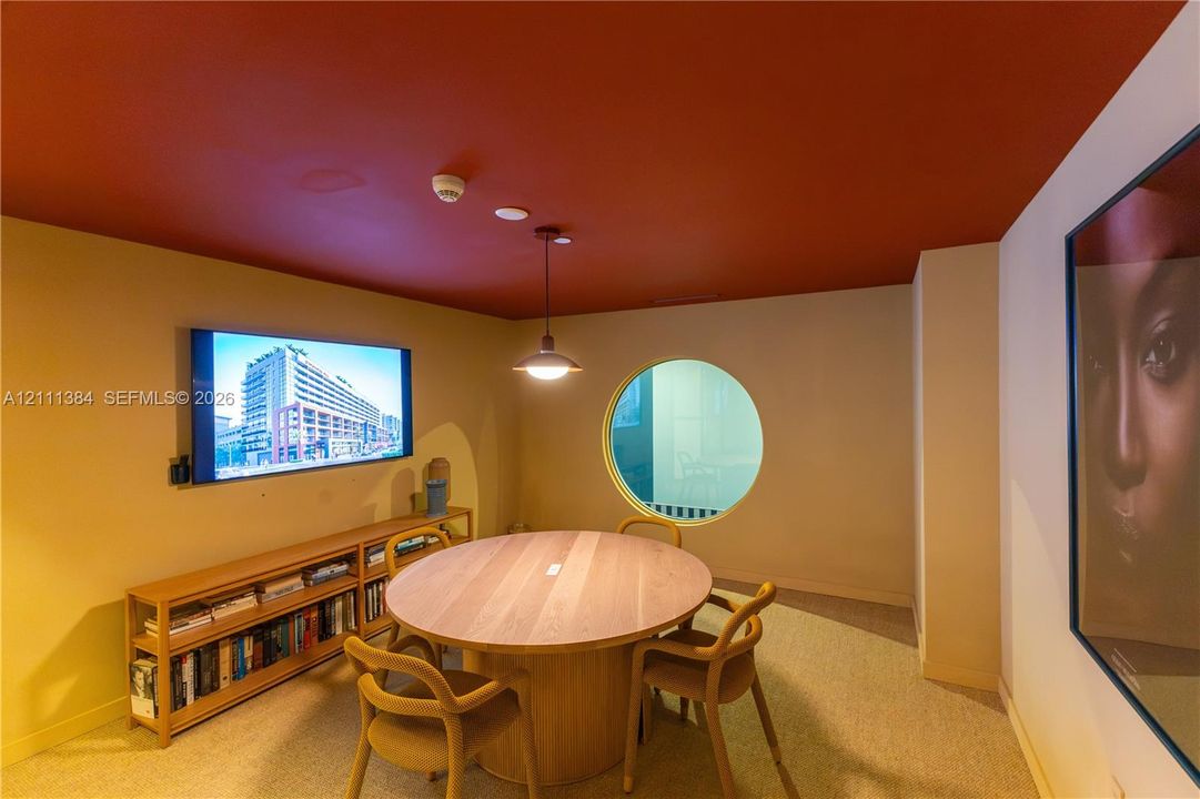Interior space featuring a circular window, built-in wooden shelving, a pendant light fixture, and a red-toned ceiling