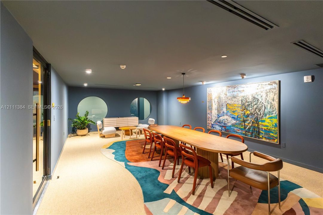 Spacious room featuring matte-finish walls, circular wall cutouts, recessed ceiling lighting, and a multi-tiered pendant light fixture