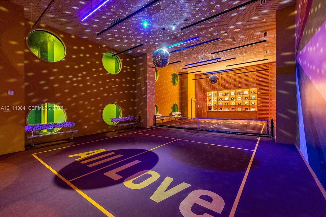 Indoor athletic court featuring circular porthole windows, custom-painted surface, built-in recessed wall shelving, and linear ceiling lighting
