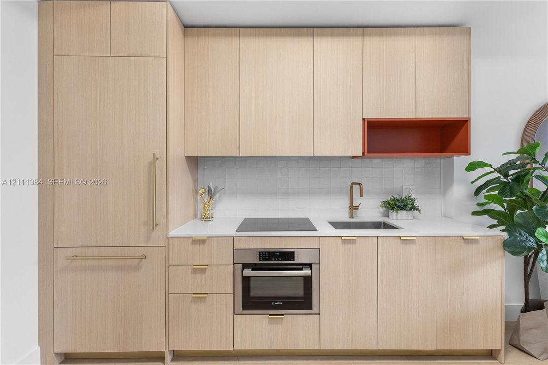 Light wood-finish cabinetry featuring integrated panel-ready refrigerator, solid-surface countertops, textured tile backsplash, built-in electric cooktop, and brass-tone hardware