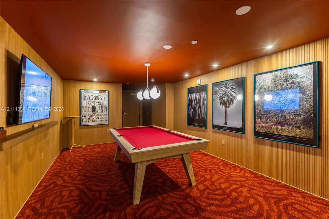 Interior space featuring vertical wood paneling, recessed lighting, a three-globe pendant fixture, and patterned wall-to-wall carpeting