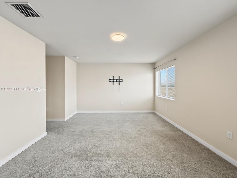 Neutral-toned interior space featuring neutral wall-to-wall carpeting, a single-pane window, and a flush-mount ceiling light fixture
