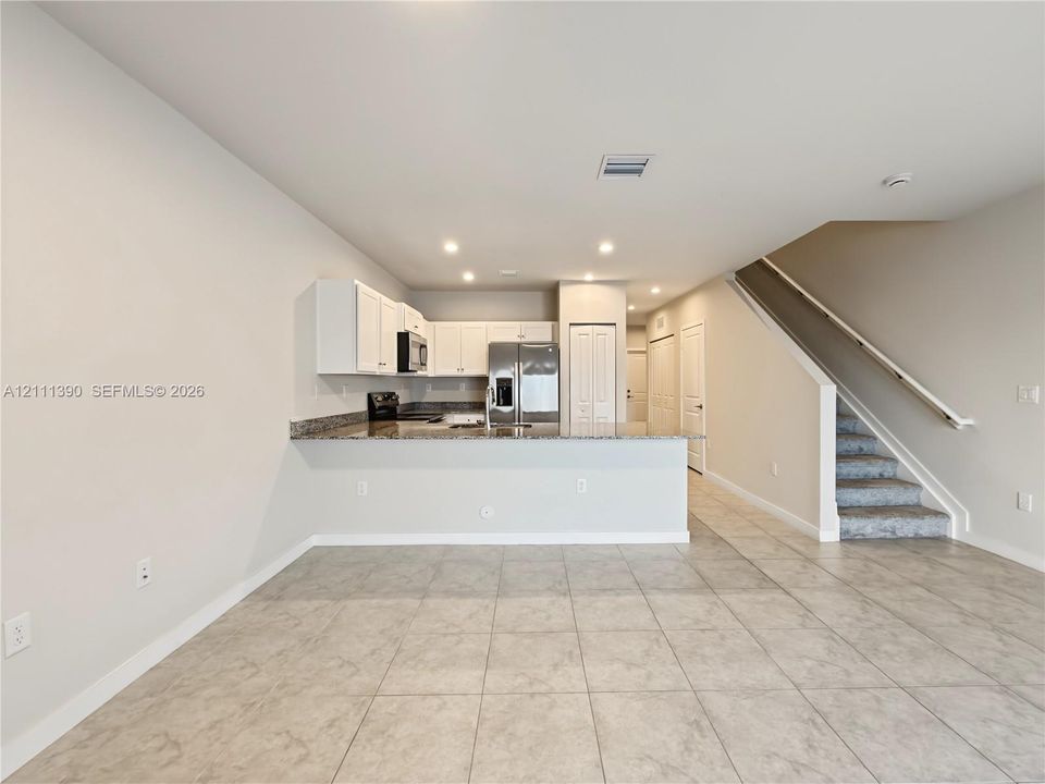 Kitchen featuring white cabinetry, stone-finish countertops, stainless steel refrigerator, recessed lighting, and tile flooring