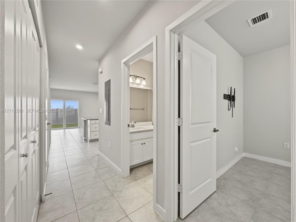Interior hallway featuring large-format tile flooring, white panel doors, and neutral wall tones