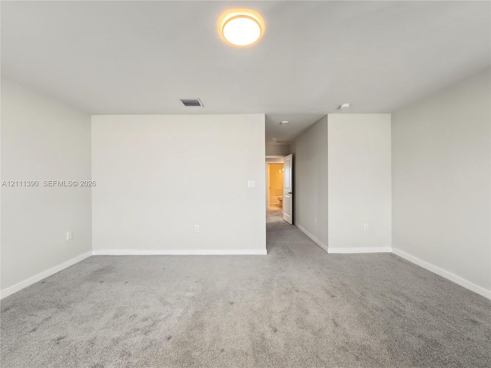Neutral-toned interior room featuring wall-to-wall carpeting and a ceiling-mounted light fixture